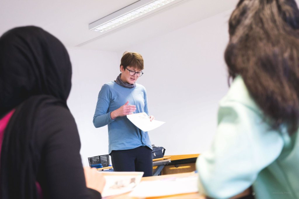 Students in foreground facing the teacher 